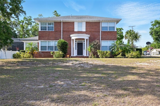 view of front facade featuring brick siding, fence, and a front yard