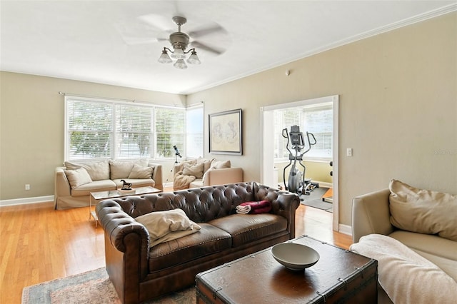 living area with crown molding, ceiling fan, baseboards, and light wood-style floors
