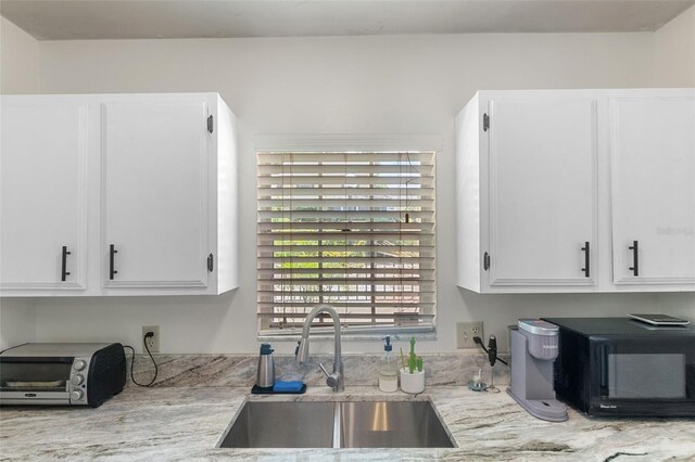 kitchen featuring white cabinetry, black microwave, a sink, and a toaster