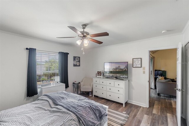 bedroom with baseboards, ceiling fan, ornamental molding, and wood finished floors