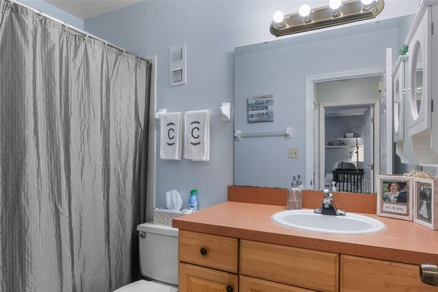bathroom featuring vanity, a shower with curtain, toilet, and visible vents