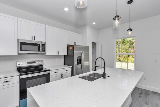 13430 SW 88th Ter, Ocala, FL 34473 - kitchen featuring a kitchen island with sink, white cabinets, a sink, decorative light fixtures, and stainless steel appliances
