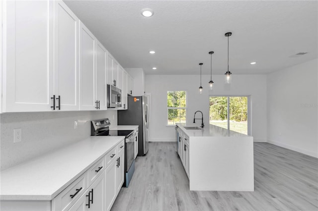 13430 SW 88th Ter, Ocala, FL 34473 - kitchen with white cabinets, a sink, an island with sink, stainless steel appliances, and baseboards
