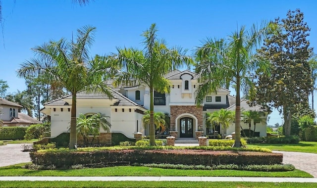 5550 Osprey Isle Ln, Orlando, FL 32819 - mediterranean / spanish-style home with driveway, stucco siding, french doors, and stone siding