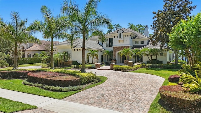 5550 Osprey Isle Ln, Orlando, FL 32819 - mediterranean / spanish-style house with curved driveway, stucco siding, a front yard, and a chimney
