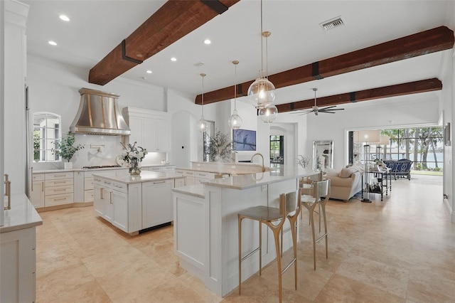 5550 Osprey Isle Ln, Orlando, FL 32819 - kitchen featuring a ceiling fan, wall chimney exhaust hood, a spacious island, and beamed ceiling