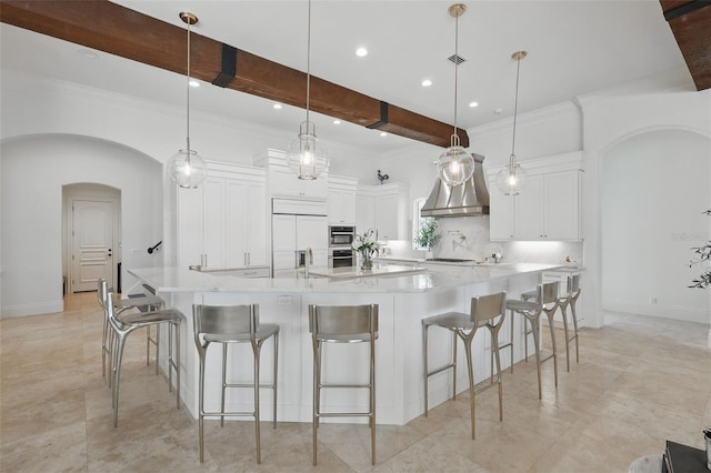 5550 Osprey Isle Ln, Orlando, FL 32819 - kitchen with beamed ceiling, a spacious island, white cabinets, custom range hood, and arched walkways
