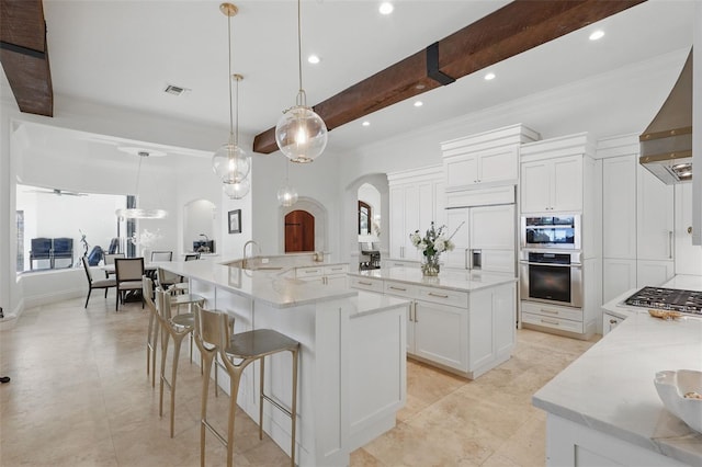5550 Osprey Isle Ln, Orlando, FL 32819 - kitchen with visible vents, arched walkways, a large island with sink, stainless steel gas stovetop, and white cabinetry