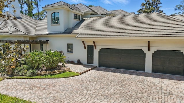 5550 Osprey Isle Ln, Orlando, FL 32819 - view of front of house featuring a tiled roof, a garage, decorative driveway, a pergola, and stucco siding