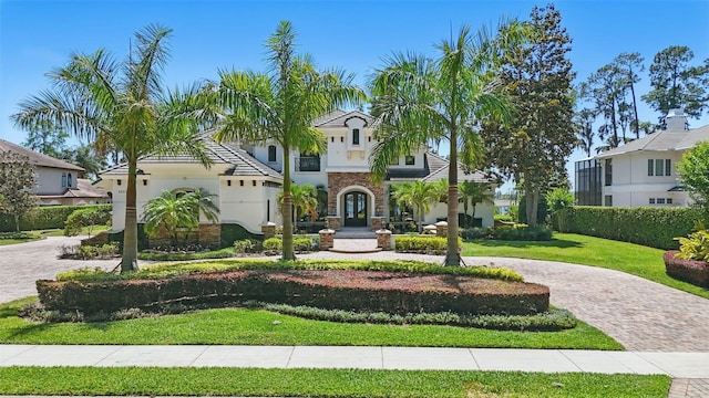 5550 Osprey Isle Ln, Orlando, FL 32819 - mediterranean / spanish-style home featuring curved driveway, stucco siding, stone siding, and a front yard