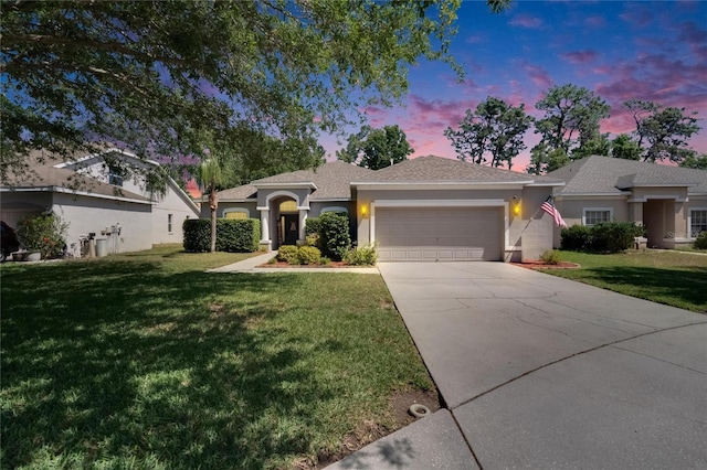 ranch-style home featuring concrete driveway, an attached garage, stucco siding, and a lawn