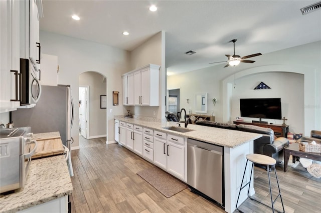 kitchen with visible vents, a sink, open floor plan, arched walkways, and appliances with stainless steel finishes