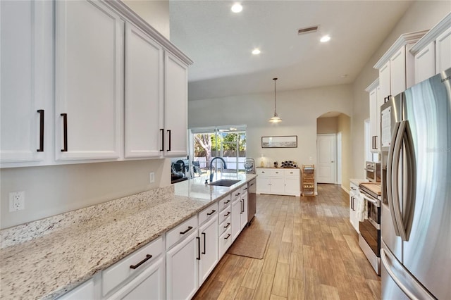 kitchen with white cabinetry, appliances with stainless steel finishes, arched walkways, and a sink