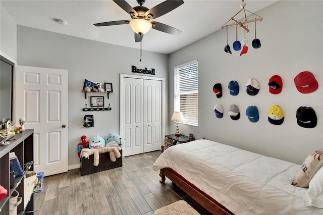 bedroom with baseboards, a closet, ceiling fan, and wood finished floors