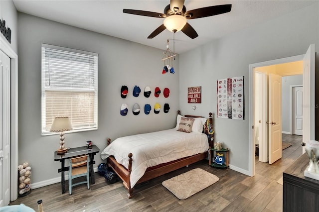 bedroom with ceiling fan, baseboards, and wood finished floors