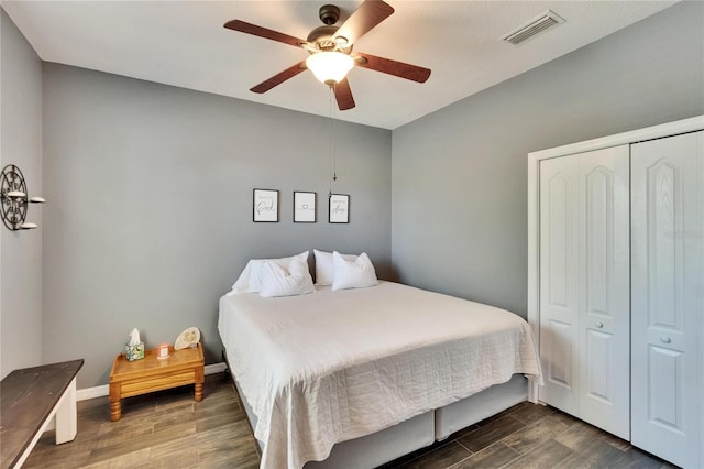 bedroom featuring a ceiling fan, a closet, visible vents, baseboards, and dark wood-style floors