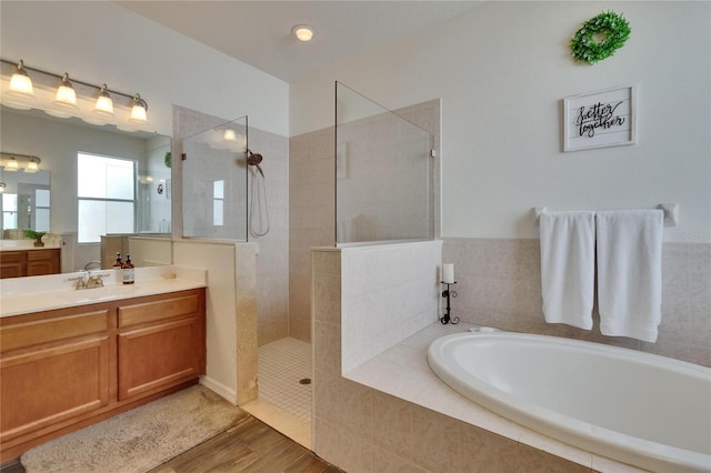 bathroom with walk in shower, vanity, a garden tub, and wood finished floors