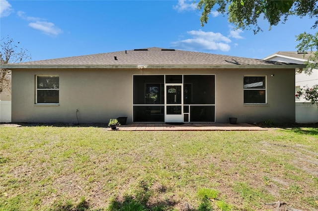 rear view of house with a lawn, stucco siding, and a sunroom