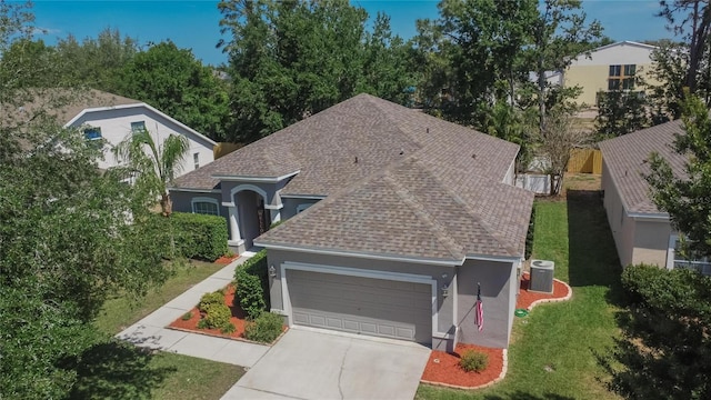 view of front facade featuring driveway, an attached garage, stucco siding, roof with shingles, and a front lawn