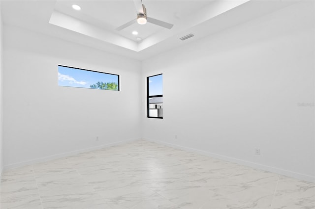 spare room with visible vents, marble finish floor, and a tray ceiling