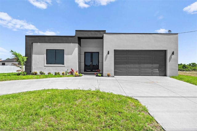 modern home with a front yard, stucco siding, french doors, concrete driveway, and an attached garage