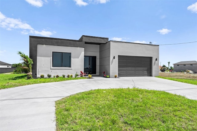 contemporary house with an attached garage, concrete driveway, stucco siding, and a front lawn