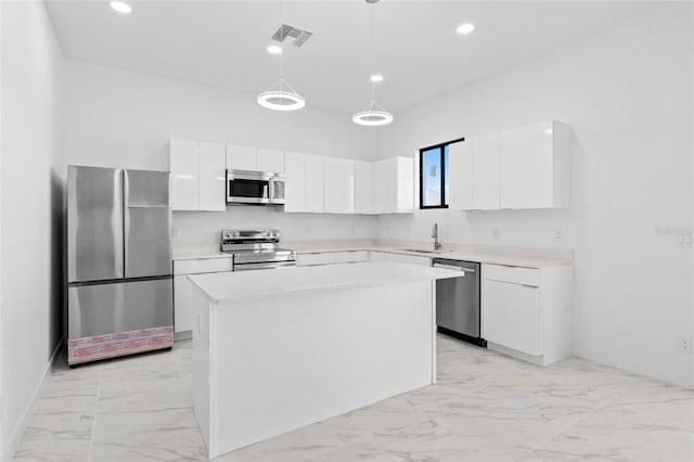 kitchen featuring white cabinets, appliances with stainless steel finishes, a sink, marble finish floor, and a kitchen island
