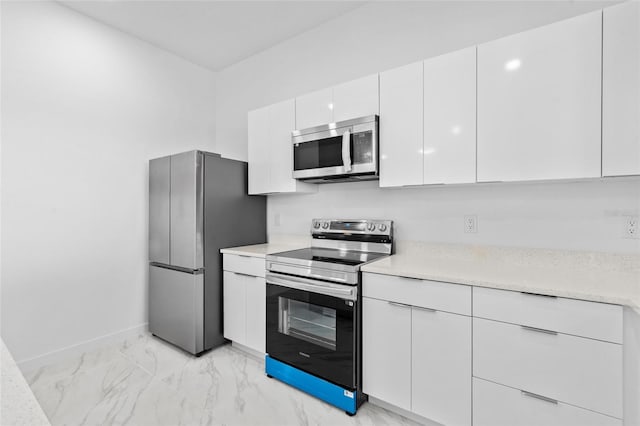 kitchen with marble finish floor, baseboards, light countertops, white cabinetry, and appliances with stainless steel finishes