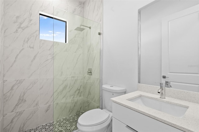 full bathroom with toilet, tiled shower, and vanity