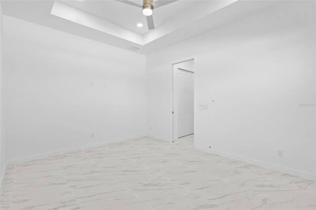 unfurnished room featuring marble finish floor, baseboards, ceiling fan, recessed lighting, and a tray ceiling