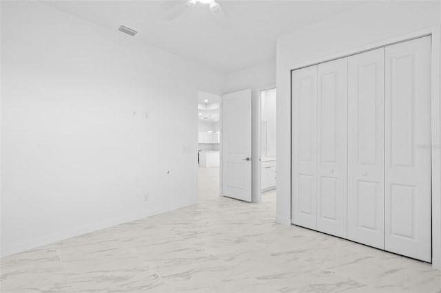 unfurnished bedroom with a closet, a ceiling fan, marble finish floor, and baseboards