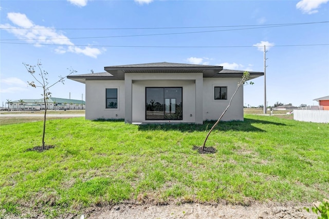 back of property with a yard and stucco siding