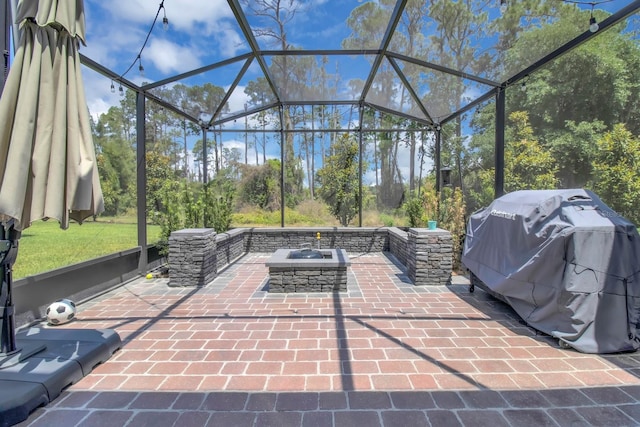 view of patio / terrace with a fire pit, glass enclosure, and area for grilling