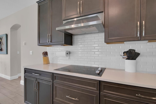kitchen featuring backsplash, black electric stovetop, under cabinet range hood, and light countertops