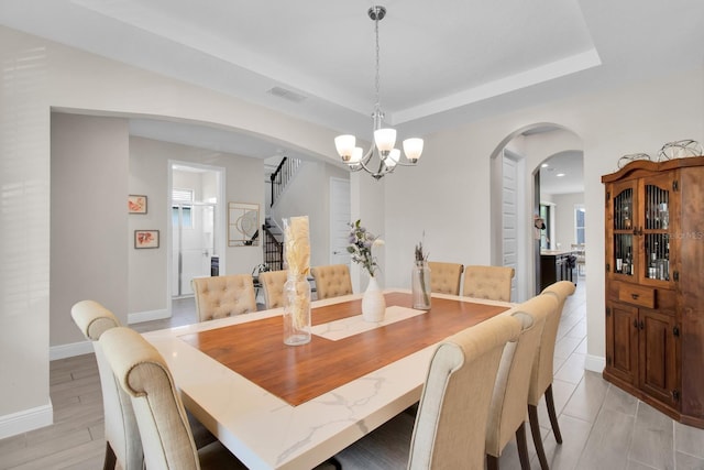 dining area featuring arched walkways, stairway, baseboards, visible vents, and a notable chandelier