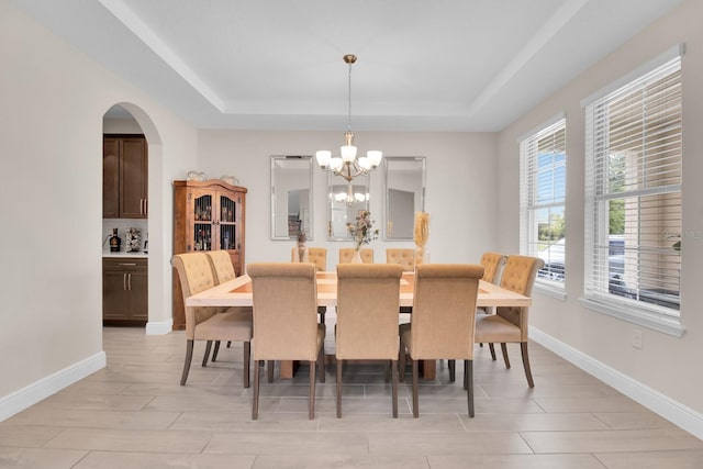 dining area featuring an inviting chandelier, baseboards, and a tray ceiling