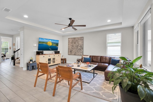 living room with recessed lighting, ceiling fan, baseboards, visible vents, and a tray ceiling