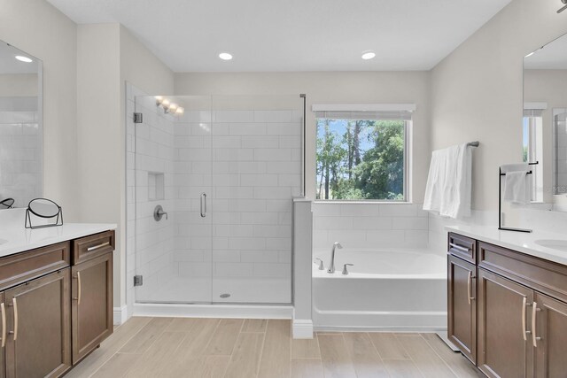 bathroom featuring a garden tub, recessed lighting, two vanities, and a shower stall