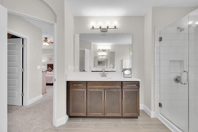 bathroom featuring ensuite bathroom, vanity, baseboards, a stall shower, and a ceiling fan