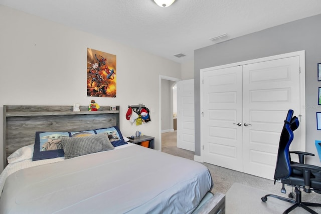 bedroom with visible vents, carpet floors, a textured ceiling, and a closet