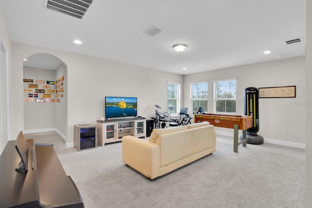 carpeted living area featuring baseboards, visible vents, and arched walkways