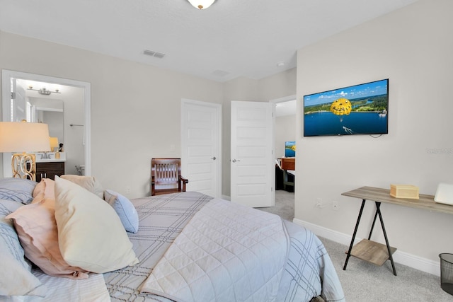 carpeted bedroom with visible vents, connected bathroom, and baseboards