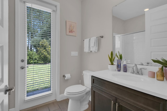 bathroom featuring a shower with shower door, a healthy amount of sunlight, toilet, and vanity