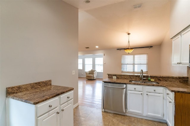 kitchen with dark stone counters, a sink, a peninsula, stainless steel dishwasher, and white cabinets