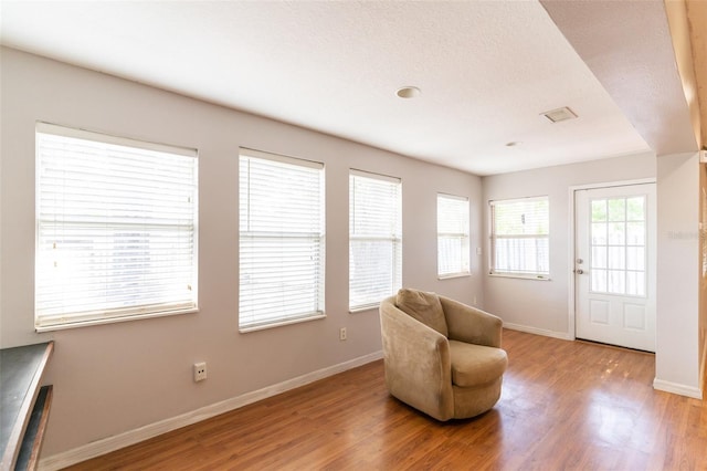 sitting room with baseboards and light wood-style flooring