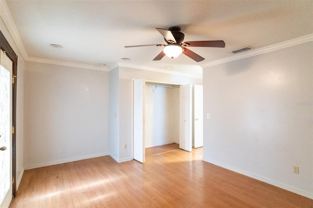 empty room featuring visible vents, a ceiling fan, crown molding, and light wood-style flooring
