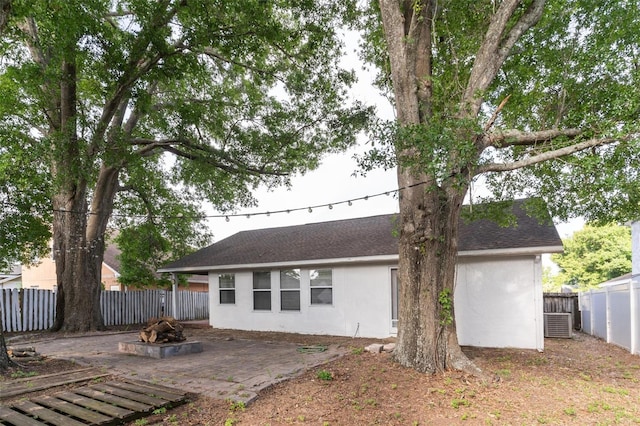 back of house featuring an outdoor fire pit, a fenced backyard, stucco siding, a shingled roof, and a patio area