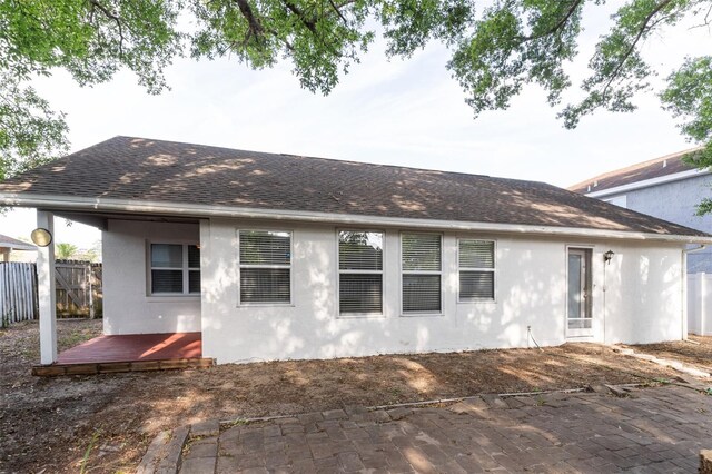 back of property featuring a deck, fence, stucco siding, and roof with shingles