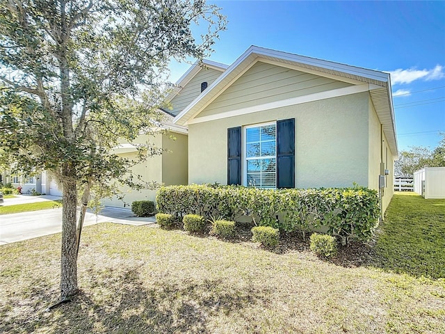 view of front facade with stucco siding, fence, concrete driveway, and a front yard