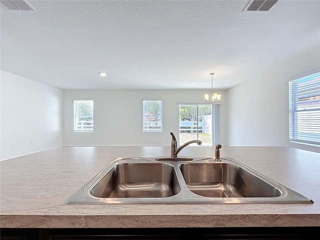 room details featuring a sink, decorative light fixtures, a chandelier, and visible vents